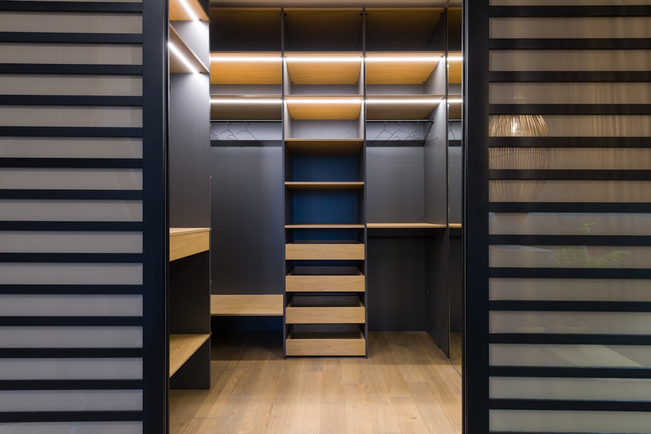 Spacious luxury walk-in closet with modern wooden shelving and stylish lighting.